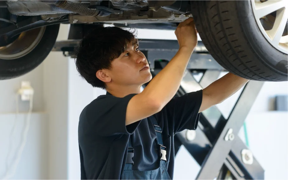 笑顔で車の整備をする男性の写真