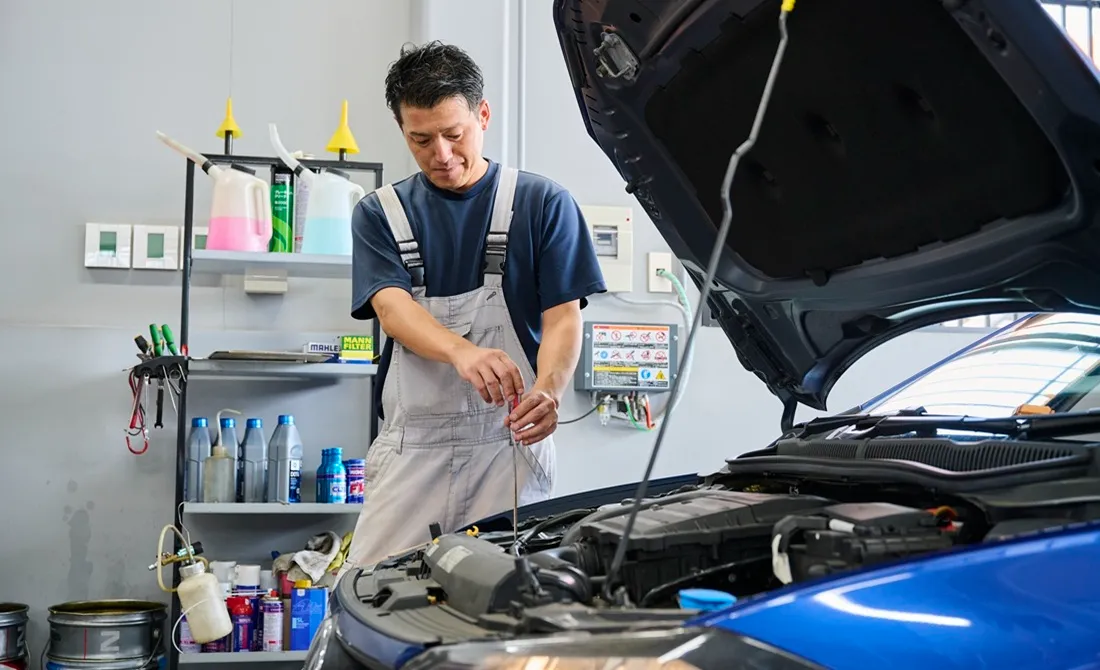 車のボンネットを開き、修理する男性の写真